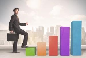 Business person climbing up on colourful chart pillars concept